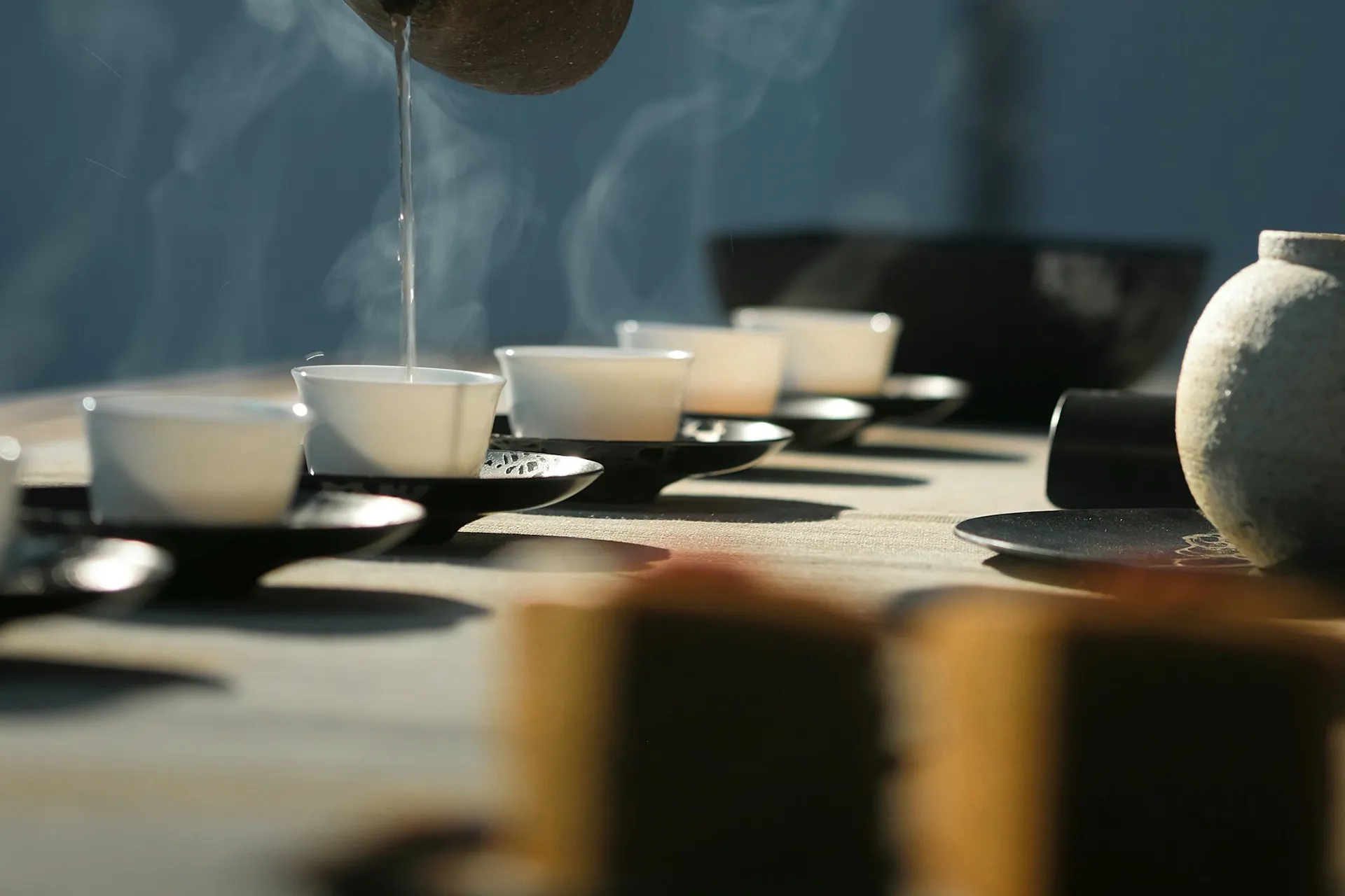 A hand pouring hot water over a white cup at a traditional tea ceremony