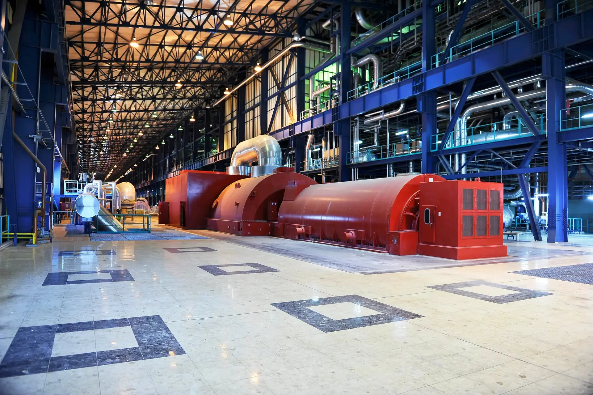 A view down a power-station turbine hall, machinery receding under a trussed roof